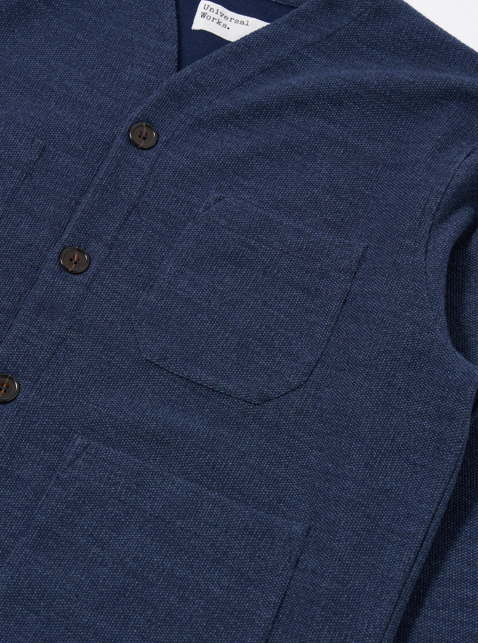 The Navy Maiorca Jersey Cardigan is displayed from the back as a flat lay against a white background. The image highlights the garment's textured, patterned jersey fabric and the soft cotton rib-bound cuffs and hem.