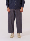A model wears the Navy Konos Cotton Judo Pant against a plain white background. The trousers feature a loose, relaxed fit, an elasticated waistband with a drawstring, and a distinctive wrap-front design. The fabric is a navy blue cotton with a subtle textured pattern. The model is shown from the waist down, paired with white socks and dark shoes.