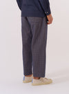 A model wears the Navy Konos Cotton Judo Pant, shown from the waist down against a plain white background. The trousers feature a relaxed, loose fit with a wide leg and a drawstring at the waist. The navy blue cotton fabric has a distinct textured appearance. The model is wearing a light-colored shirt tucked in and dark footwear.