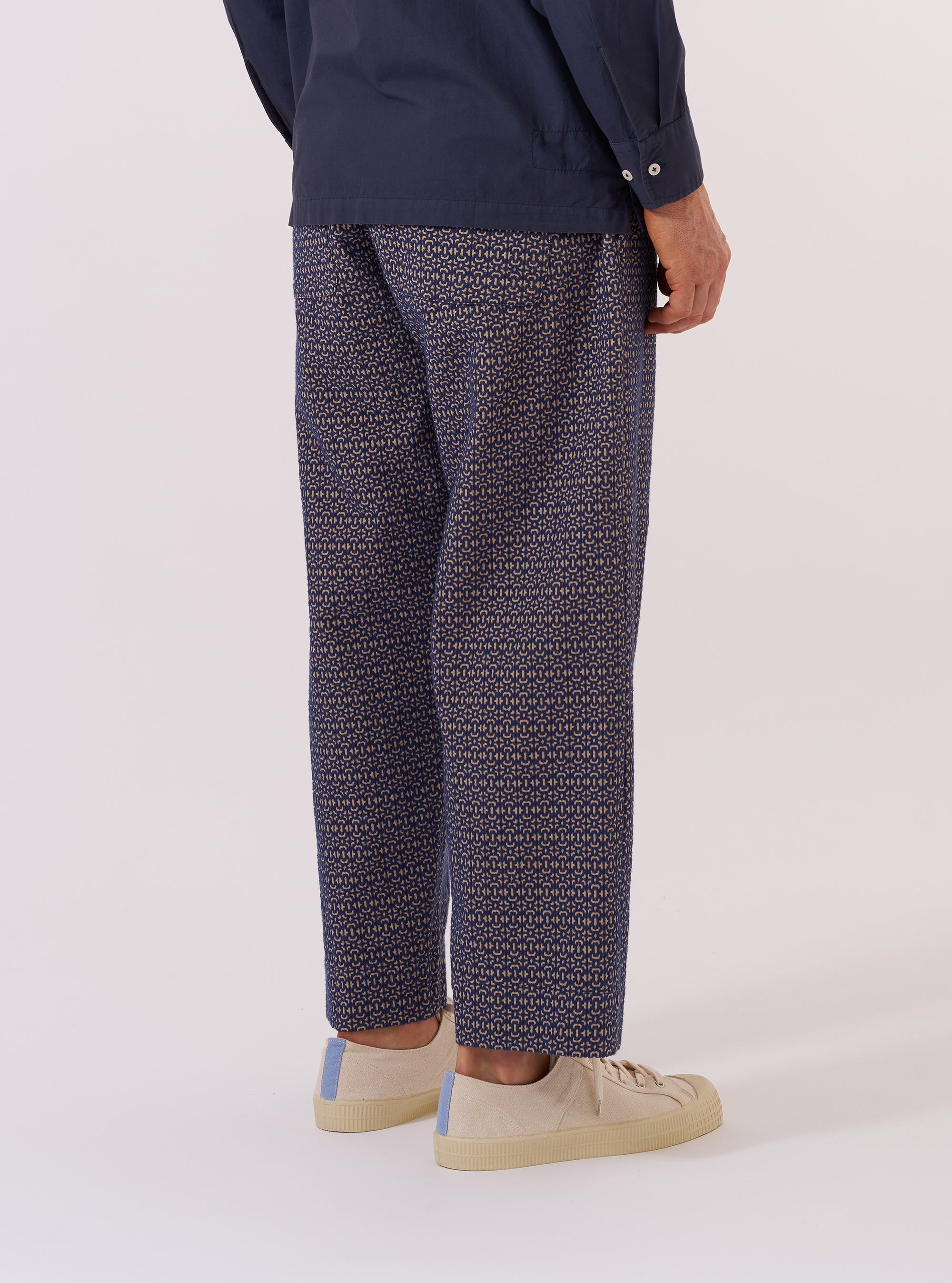A model wears the Navy Konos Cotton Judo Pant, shown from the waist down against a plain white background. The trousers feature a relaxed, loose fit with a wide leg and a drawstring at the waist. The navy blue cotton fabric has a distinct textured appearance. The model is wearing a light-colored shirt tucked in and dark footwear.