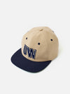 The Sand/Navy Canvas Baseball Hat is shown from a rear angle as a flat lay against a plain white background. The hat features a sand-colored canvas crown with a contrasting navy blue adjustable strap and a navy blue peak. Two embroidered eyelets are visible on the rear panels.