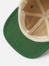 The Sand/Navy Canvas Baseball Hat is shown from the back as a flat lay against a plain white background. The hat features a sand-colored canvas crown and a navy blue adjustable strap with a metal buckle. The construction includes visible stitching and embroidered eyelets.