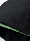 The Black Canvas Baseball Hat is shown from the back as a flat lay against a plain white background. The image highlights the adjustable leather strap with a silver-tone metal clasp and a small woven logo tab. The hat is made from a solid black cotton canvas fabric with visible topstitching and embroidered eyelets.