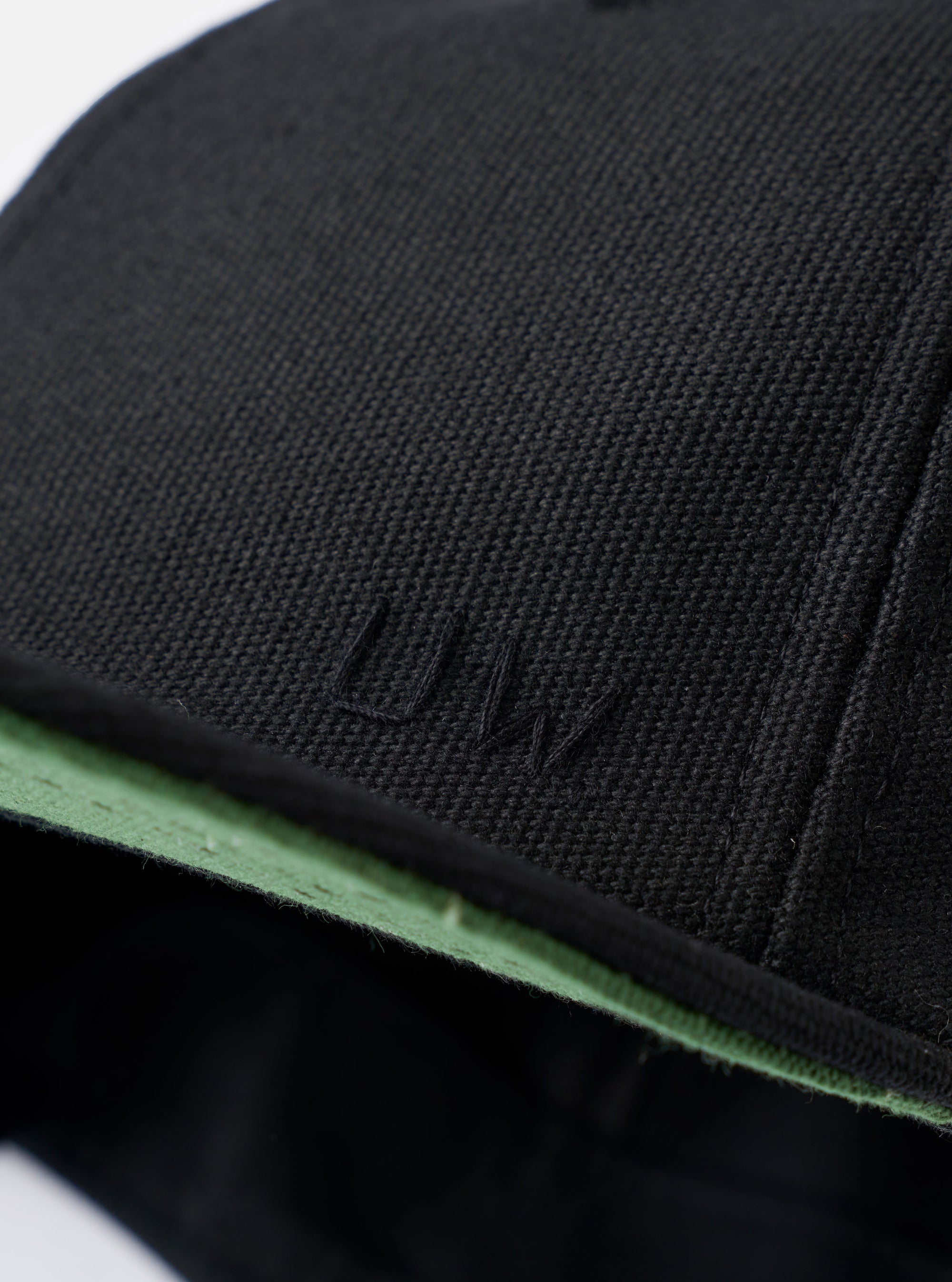 The Black Canvas Baseball Hat is shown from the back as a flat lay against a plain white background. The image highlights the adjustable leather strap with a silver-tone metal clasp and a small woven logo tab. The hat is made from a solid black cotton canvas fabric with visible topstitching and embroidered eyelets.
