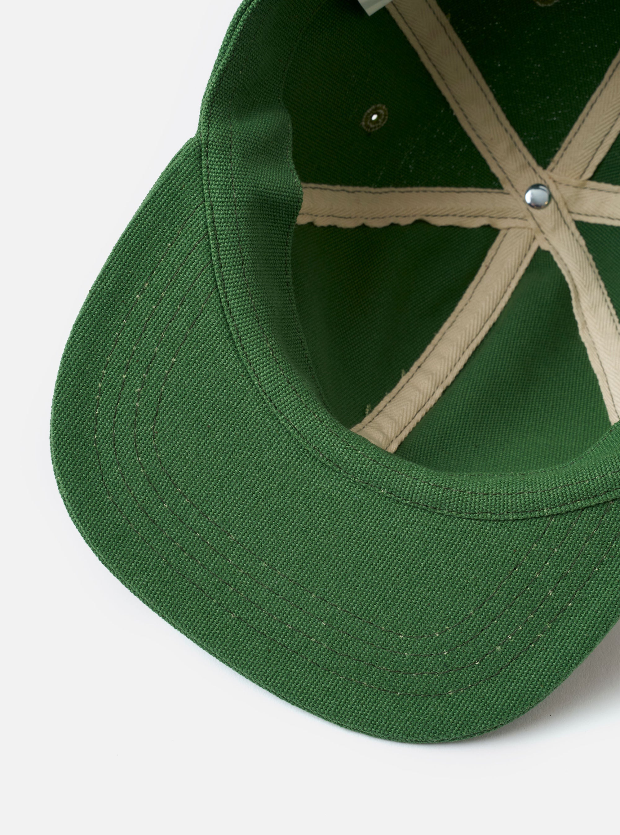 The Green Canvas Baseball Hat is displayed from a rear angle as a flat lay against a plain white background. The image highlights the adjustable fabric strap with a metal buckle and the tonal embroidered eyelets on the crown panels. The green canvas material shows a sturdy texture and clean stitching.