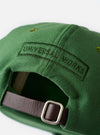 The Green Canvas Baseball Hat is shown in a close-up detail shot against a plain white background. The image highlights the durable texture of the green cotton canvas fabric, focusing on the six-panel construction, tonal stitching, and an embroidered ventilation eyelet.