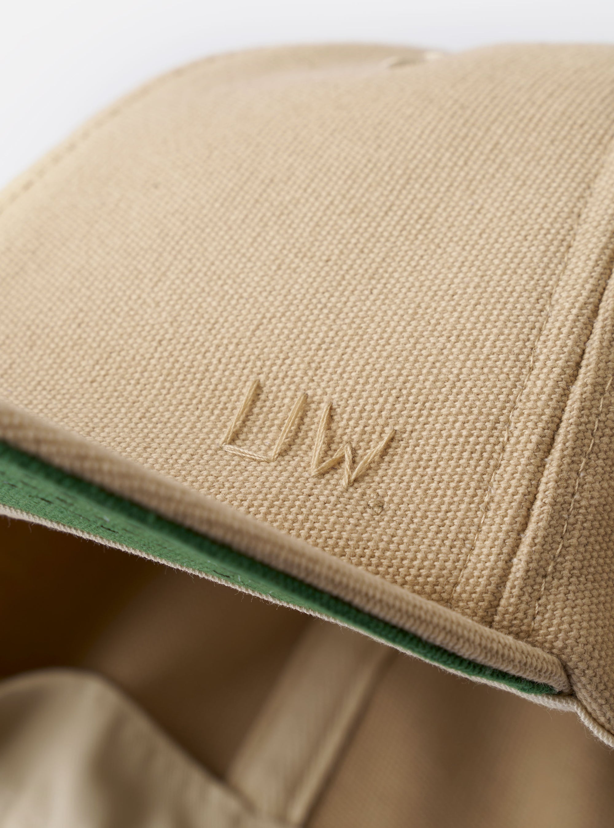 The Sand Canvas Baseball Hat is shown from a rear three-quarter angle as a flat lay against a plain white background. The image highlights the adjustable fabric strap with a metal buckle and the structured six-panel construction of the crown. The sand-colored cotton canvas fabric has a smooth, durable texture.