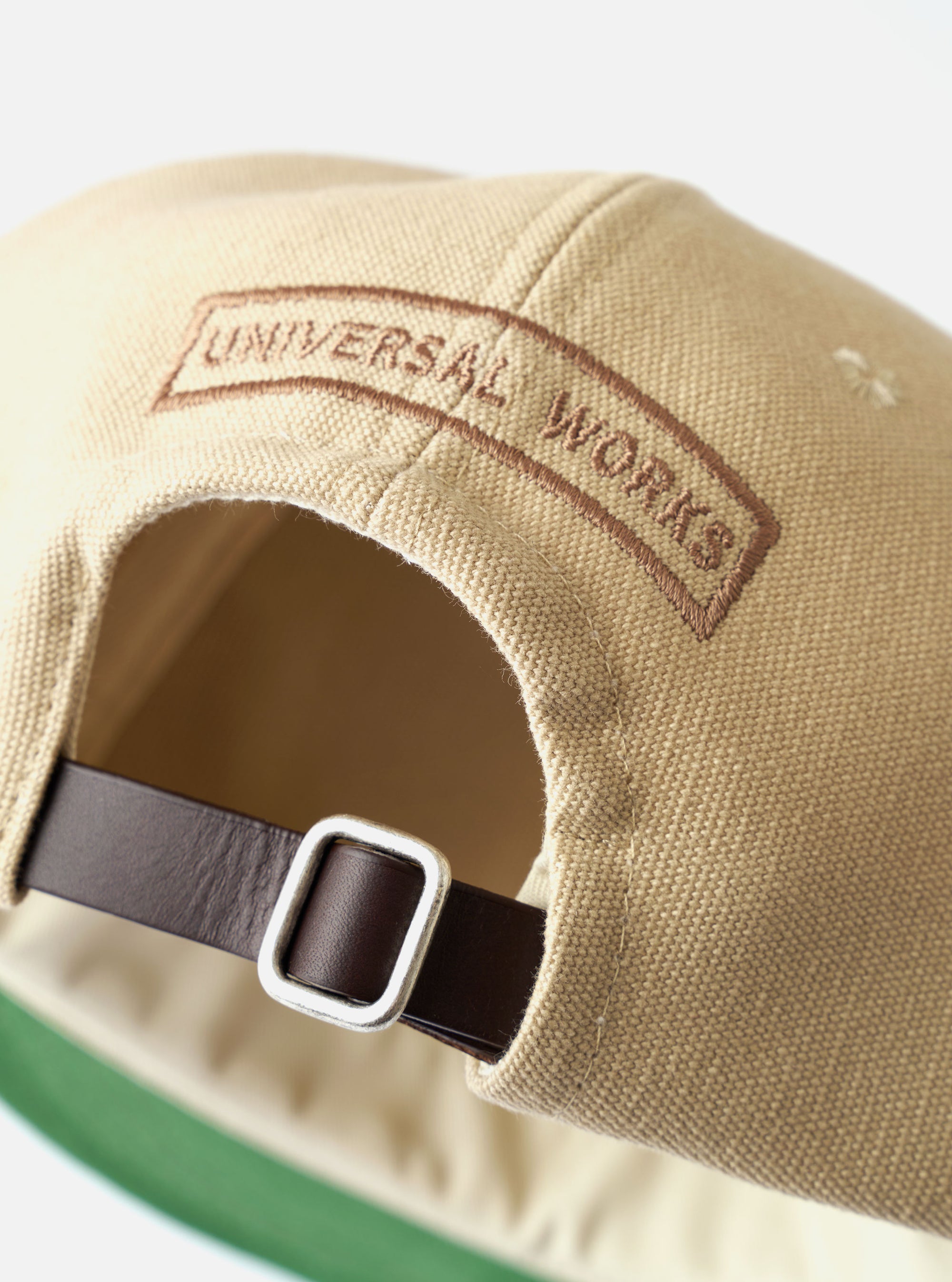 The Sand Canvas Baseball Hat is shown as a flat lay against a plain white background. The image displays the six-panel cap in a light sand color, featuring a curved brim and tonal embroidered eyelets. The cotton canvas fabric has a visible, durable texture.