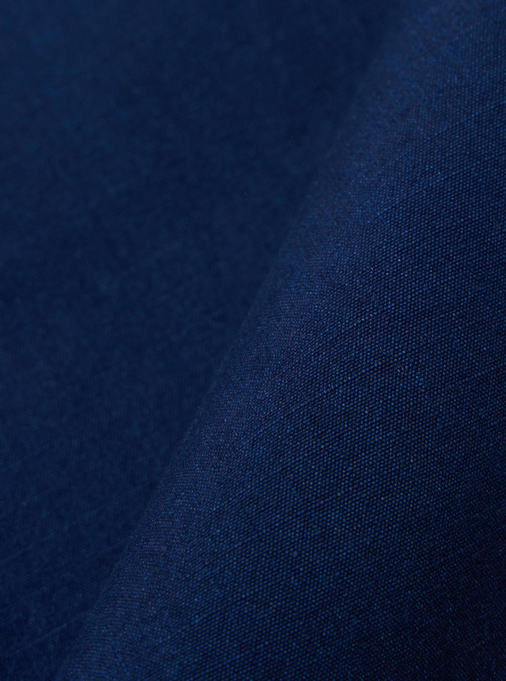 A close-up fabric swatch image of the Indigo Kimstop Two Button Jacket shows a deep indigo-blue textile with a visible ripstop grid pattern. The organic cotton fabric has a textured, matte finish.