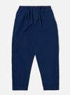 The Indigo Kimstop Pleated Track Pant is shown as a flat lay against a white background. The trousers feature an elasticated waistband with a drawstring, a single pleat at the front, and two side pockets. The fabric is a dark indigo organic cotton with a visible ripstop texture.