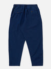 The Indigo Kimstop Pleated Track Pant is shown from the back as a flat lay against a plain white background. The trousers feature an elasticated waistband and two rear patch pockets. The garment is made from a dark indigo organic cotton fabric with a visible textured weave.