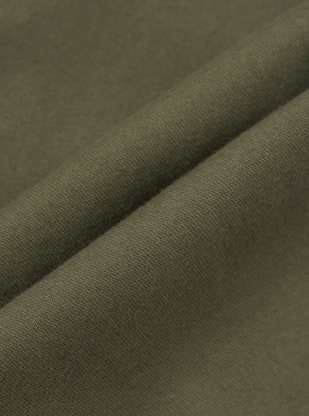 Close-up detail shot of olive brushed moleskin fabric, showing a folded edge that highlights the fine knit texture and soft surface finish. The solid, muted khaki-green cloth has a dense, smooth hand visible across the fold. No background is visible.