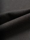 Close-up detail shot of the black single jersey fabric used in the Core Tee, showing a fine knit texture with a soft, slightly raised surface. The material is folded to reveal its weight and drape. Shot against a dark grey seamless backdrop.