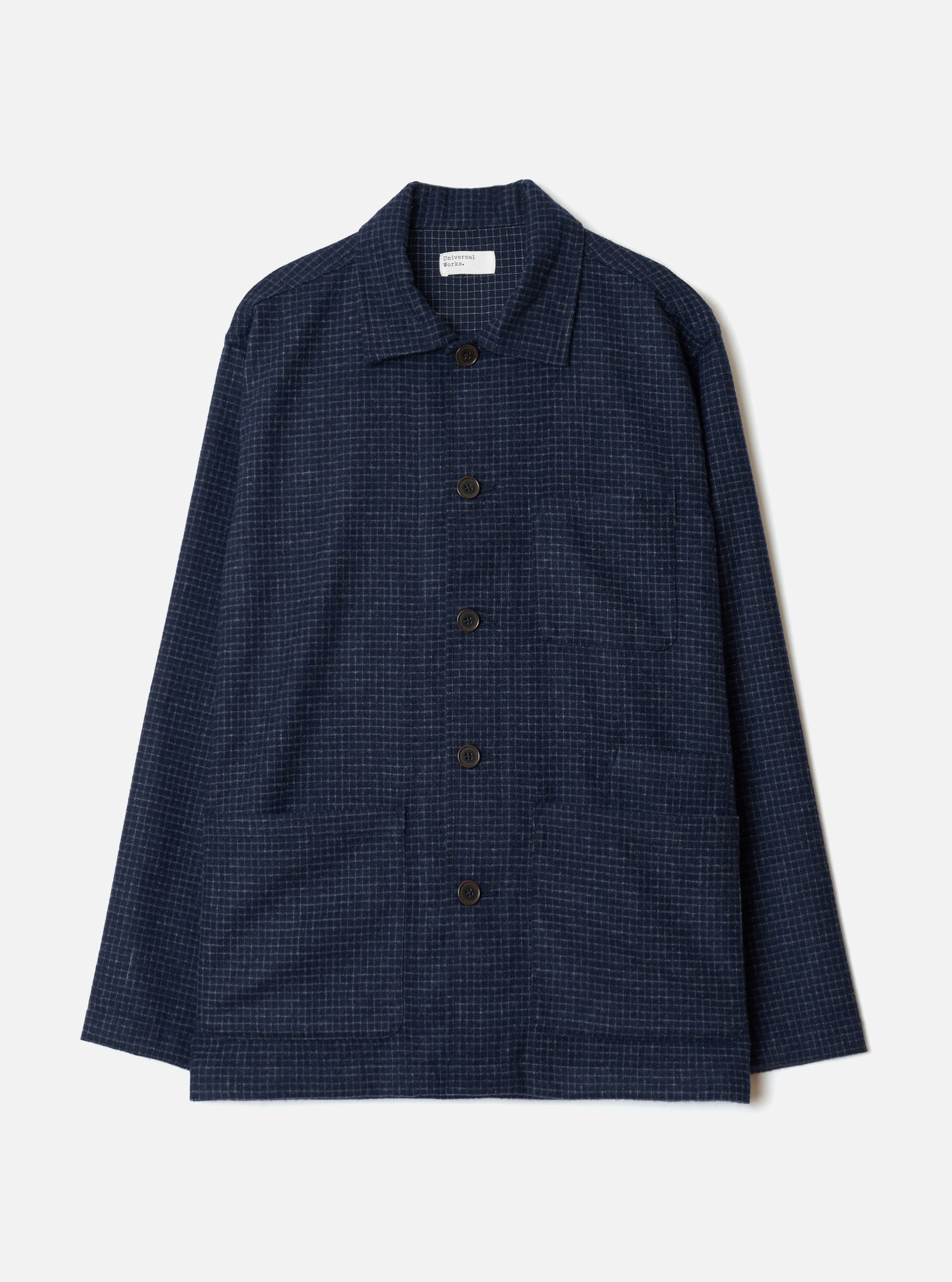 Navy check wool mix bakers overshirt in a fine grid check pattern on a plain light grey studio backdrop. Flat lay. Camp collar, five dark horn-effect buttons down the centre front, one chest patch pocket and two large lower patch pockets. Long sleeves with plain cuffs. Universal Works woven label visible at the neck.