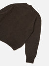 Dark brown alpaca knit cardigan laid flat on a white studio surface, shot from above at an angle. The body, one sleeve, ribbed hem, and ribbed cuff are visible. The fabric has a soft, slightly fluffy texture with a fine, plain knit construction.