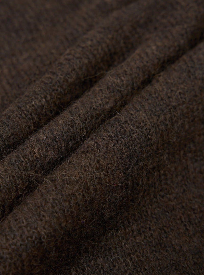 Close-up detail shot of the brown alpaca knit fabric of the David Cardigan, showing soft, fluffy fibres with a hairy, textured surface. Three gentle folds run diagonally across the frame, highlighting the fabric's depth and loft. The dark brown marl tone shows subtle variation throughout.