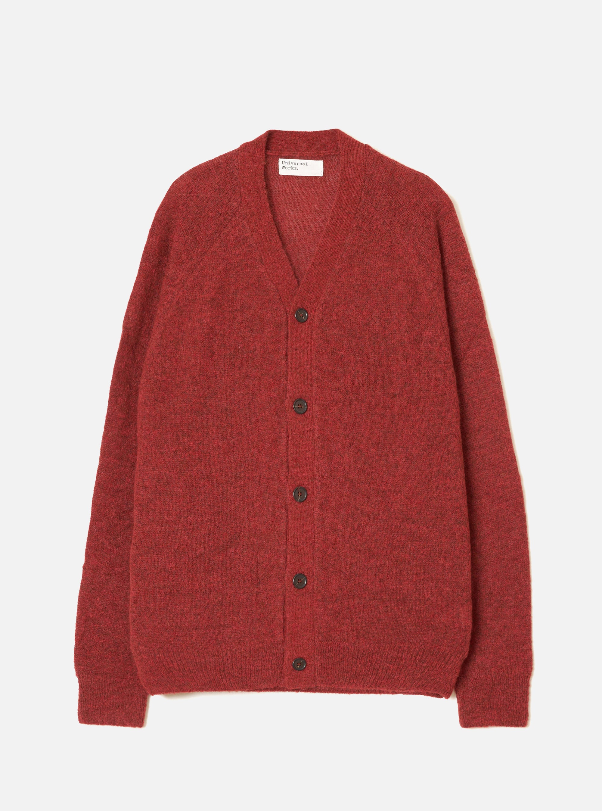 Deep orange alpaca knit cardigan laid flat on a light grey studio backdrop. V-neckline with a woven Universal Works label at the back neck. Five dark brown buttons run down the centre front. Raglan sleeves with ribbed cuffs and a ribbed hem. Soft, fluffy knit texture throughout.