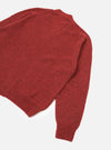 Deep orange marl alpaca knit cardigan, flat lay on a white studio surface. Shot shows the upper body and one full sleeve at an angle. Ribbed hem and ribbed cuff are visible. The fine, soft knit texture is evident across the body and sleeve.