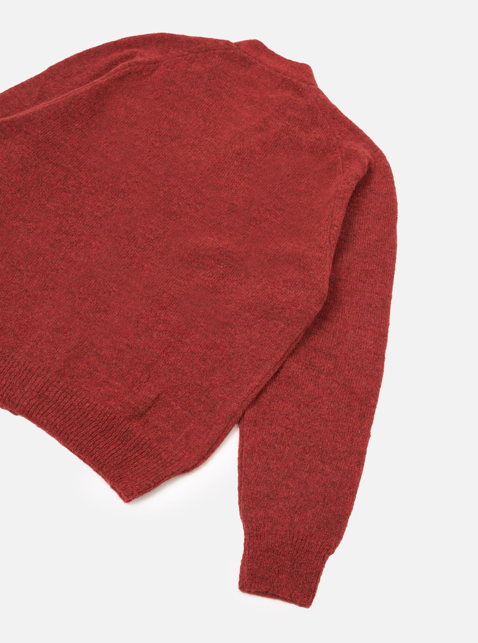 Deep orange marl alpaca knit cardigan, flat lay on a white studio surface. Shot shows the upper body and one full sleeve at an angle. Ribbed hem and ribbed cuff are visible. The fine, soft knit texture is evident across the body and sleeve.