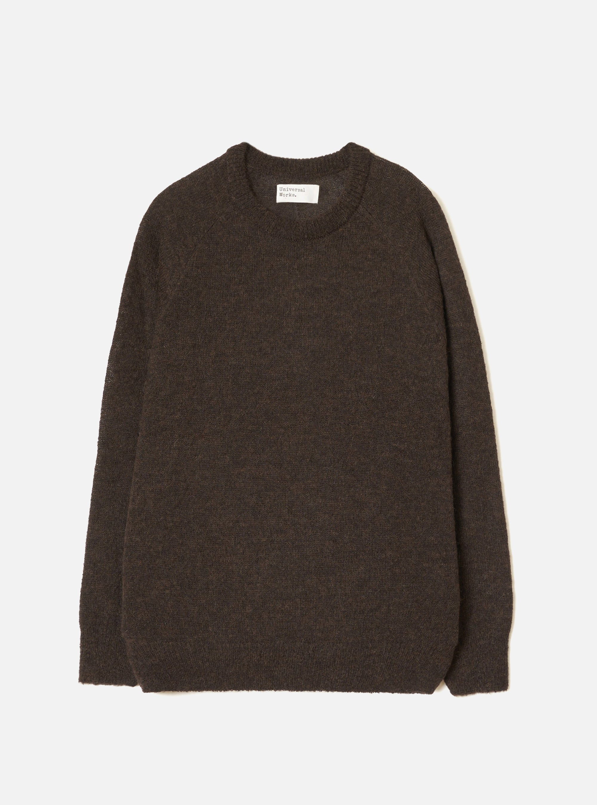 Brown alpaca knit crew neck sweater laid flat on a light grey studio backdrop. Ribbed crew neck collar with a woven Universal Works label at the back. Soft, slightly fluffy alpaca knit texture throughout. Ribbed cuffs and hem. Long sleeves. No fastenings.