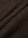 Close-up detail shot of the brown alpaca knit fabric, showing a hairy texture with visible individual fibres. Three soft ridges of folded knit run diagonally across the frame, highlighting the fabric's lofty, textured hand. Dark brown melange colouring throughout.