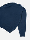 Navy alpaca knit crew neck jumper, flat lay on a light grey seamless backdrop. Shot shows the back and one sleeve at an angle, cropped at the collar and left side. Soft, slightly fluffy knit texture throughout with a ribbed hem and ribbed cuff visible at the sleeve end.