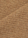 Close-up of the tawny eco wool fabric on the zip cardigan, showing a chunky, open-knit texture with a hairy, brushed finish. The warm camel-brown yarn has visible flecks of darker and lighter tones throughout. A fold in the fabric runs diagonally across the frame.