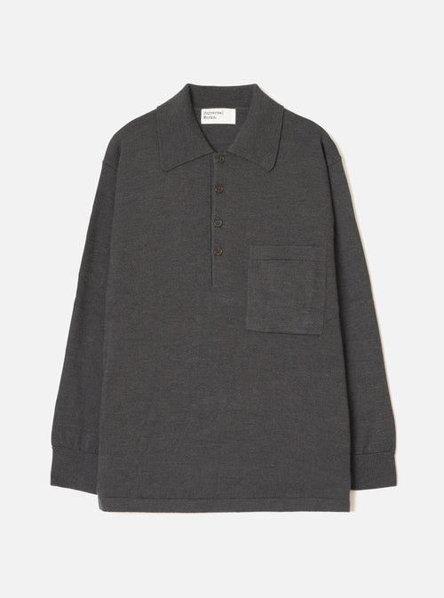 Charcoal merino knit pullover shirt laid flat on a light grey seamless backdrop. Features a wide point collar, four-button placket with dark buttons, a left chest patch pocket, long sleeves with ribbed cuffs, and a ribbed hem. Fine smooth knit texture throughout. Universal Works woven label at back neck.