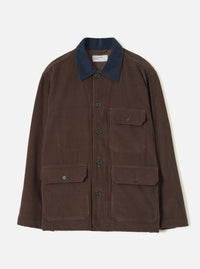 Cacao brown corduroy utility jacket laid flat on a light grey backdrop. Features a contrast navy corduroy collar, five dark buttons down the front placket, one buttoned chest patch pocket, and two large buttoned patch pockets at the hip. A Universal Works woven label sits inside the collar.