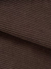Close-up of the cacao brown corduroy fabric of the utility jacket, showing wide-wale cord texture with soft, dense pile. A folded edge runs diagonally across the frame, revealing the fabric's thickness. No background visible.