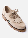 The Paraboot x Universal Works Thiers/Jannu in Sand Leather/Suede is shown from a rear three-quarter angle as a flat lay against a plain white background. The image highlights the light beige sand color, the contrast between the smooth leather and textured suede-like reverse panels, and the vulcanised natural rubber sole. The piped seams and Blake stitch construction are visible.