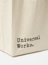 Close-up of an Ecru Cotton Canvas Tote Bag on a white surface. The bag has 'Universal Works.' printed on it in black.