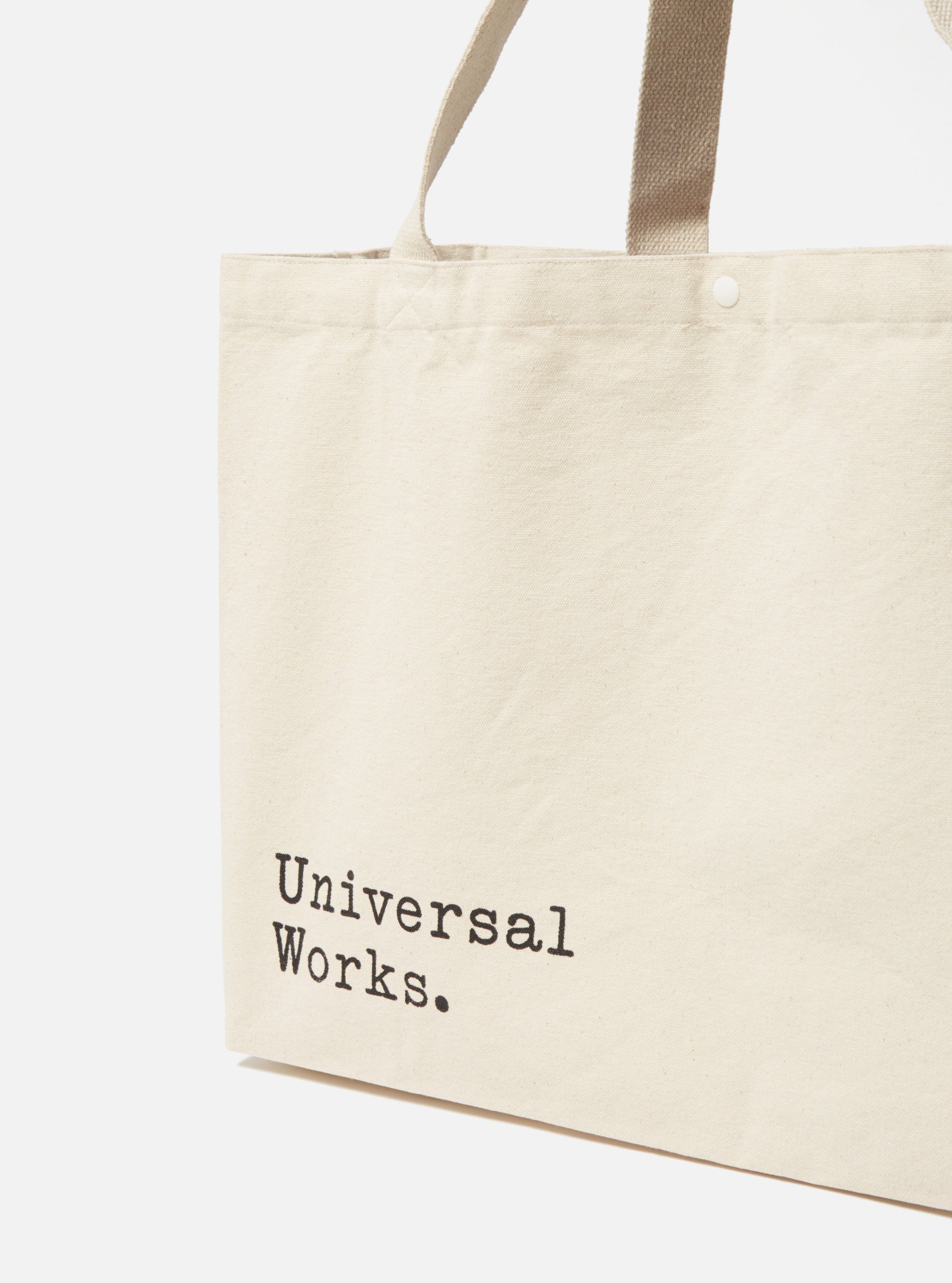 Close-up of an Ecru Cotton Canvas Tote Bag on a white background. The bag features black text and matching handles.