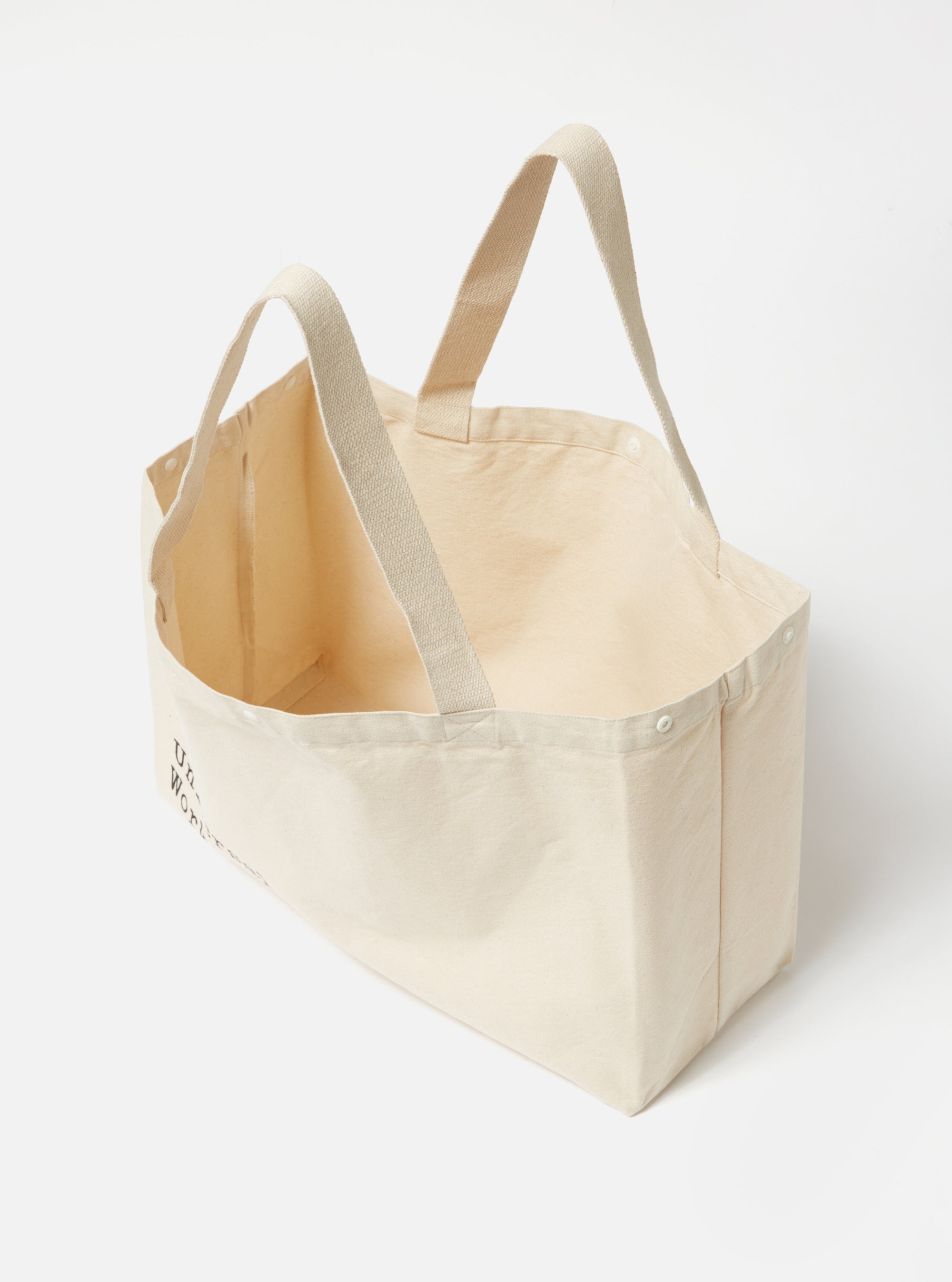 Studio shot of an Ecru Cotton Canvas Tote Bag. The bag is a light beige color and made of a thick canvas material. The background is a plain white.