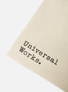 Close-up of an ecru Cotton Canvas Tote Bag on a white background. The bag features black text that reads "Universal Works."