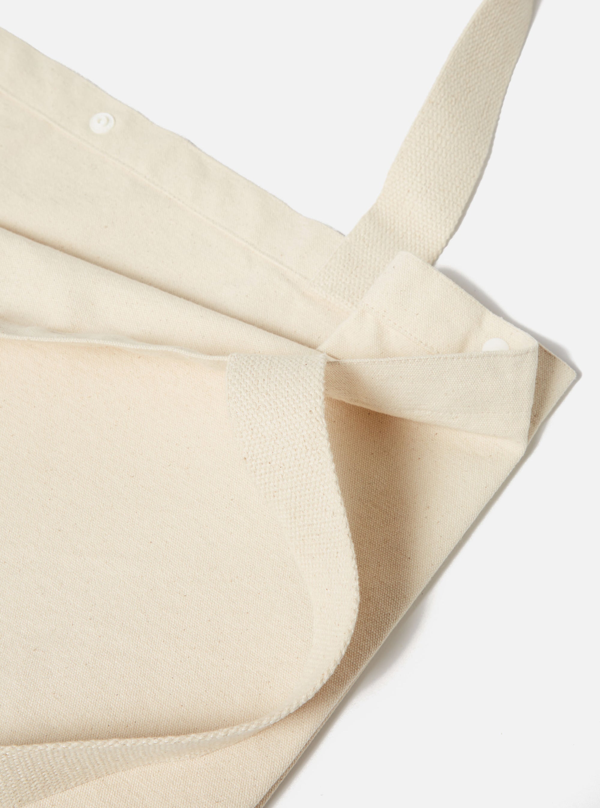 Close-up of an Ecru Cotton Canvas Tote Bag on a white background. The bag is folded, showing the texture of the cotton and the straps.