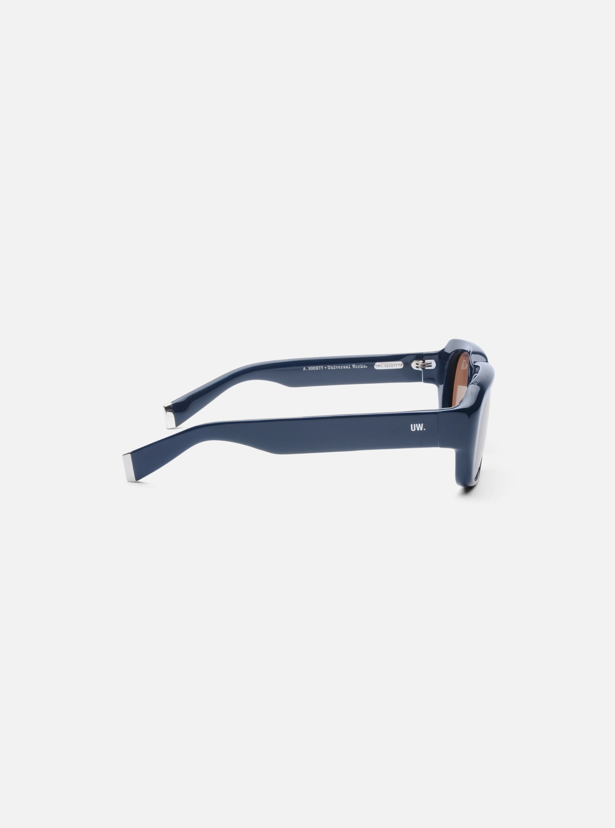 Side view of A. SOCIETY x Universal Works Navy Aberdeen Sunglasses on a white background. The frames are navy with silver accents. The lenses are a light brown tint.