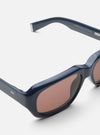 Close-up of A. SOCIETY x Universal Works Navy Aberdeen Sunglasses on a white surface. Features a navy frame and light brown lenses.