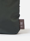Close-up of the F/CE.® Grey 420 re/cor Sacoche showing the material texture and logo tag on a white background. The sacoche is a dark grey color.