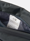 Close-up of the inside of the F/CE.® Grey 420 re/cor Sacoche, showing the grey material and a white tag with care instructions. Shot on a white background.