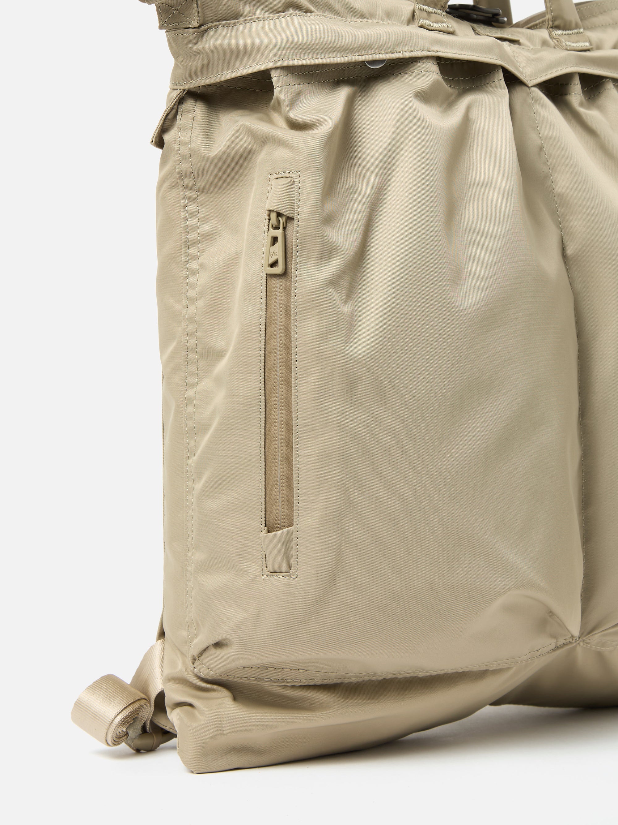 Close-up of the F/CE.® Sage Green Recycled Twill 3-Way Helmet Bag on a white background. Shows the texture of the sage green recycled twill and the zipper detail.