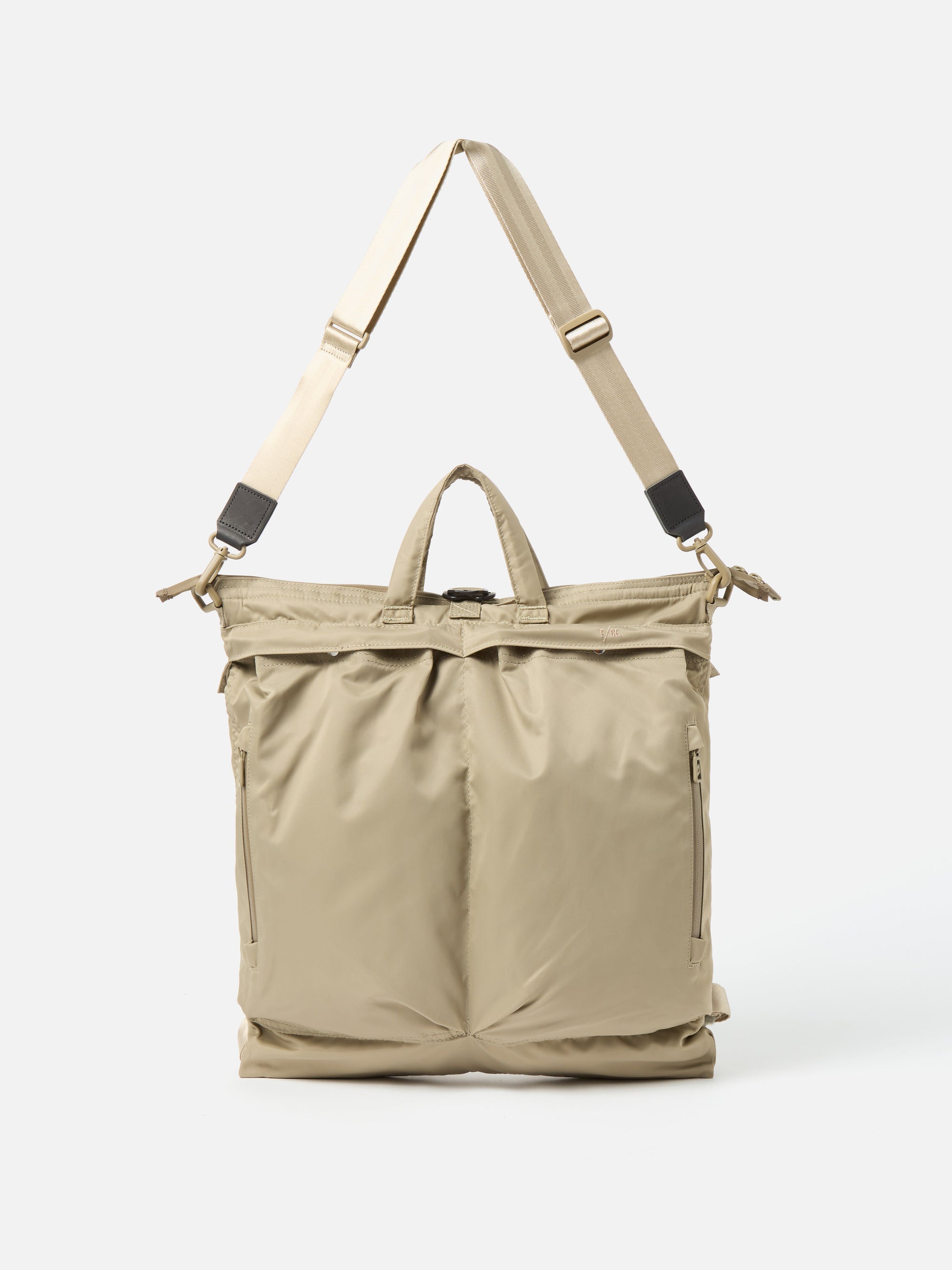 The F/CE.® Sage Green Recycled Twill 3-Way Helmet Bag is displayed on a white background. The bag features a sage green twill material and a beige strap.