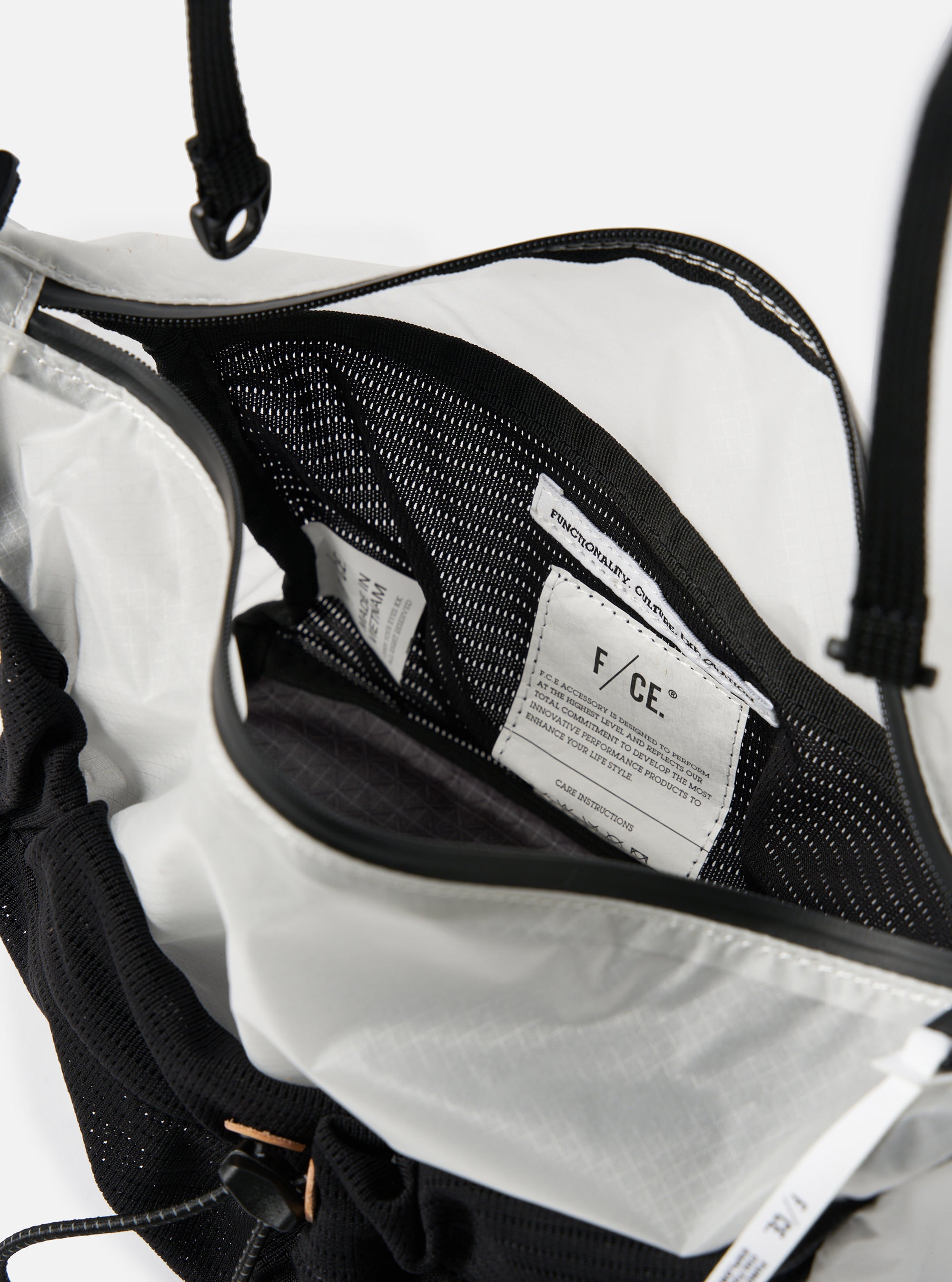 Close-up of the F/CE.® White Nylon Cordura Sil Sacoche, showing its interior. The bag features white nylon and black mesh details. The background is a clean, bright white.