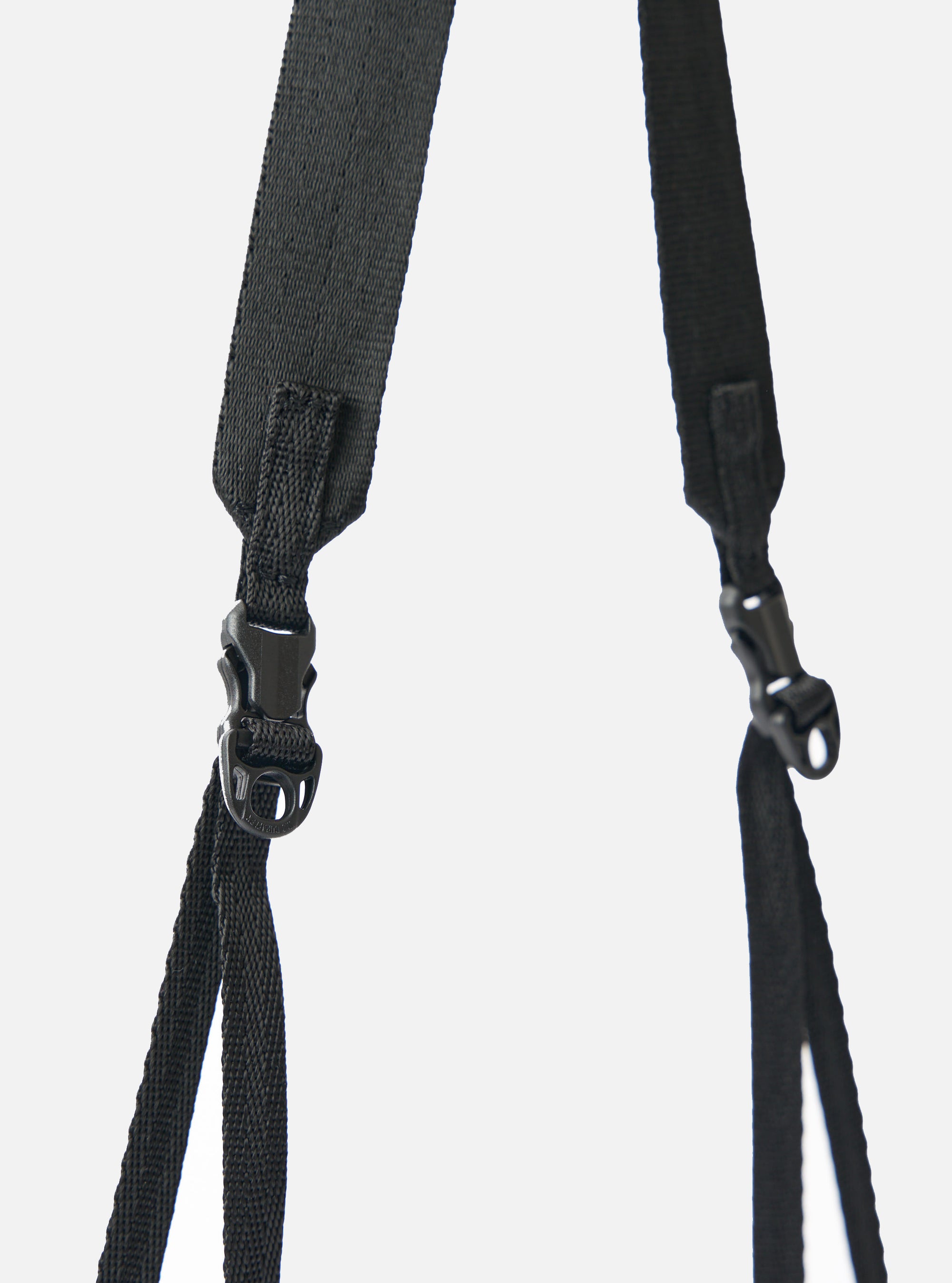 Close-up of the black nylon textured twill drawstring sacoche strap and buckle against a white backdrop. The F/CE.® sacoche is durable and stylish.