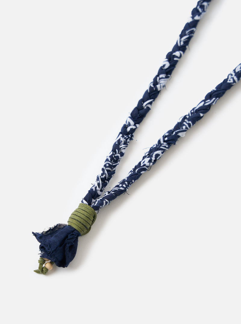 Close-up of the Hanami of Rome Blue/Military Green Leather Bandana Necklace No.57 on a white surface. The necklace features a blue and white braided fabric and a green leather detail.