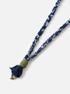 Close-up of the Hanami of Rome Blue/Military Green Leather Bandana Necklace No.57 on a white surface. The necklace features a blue and white braided fabric and a green leather detail.