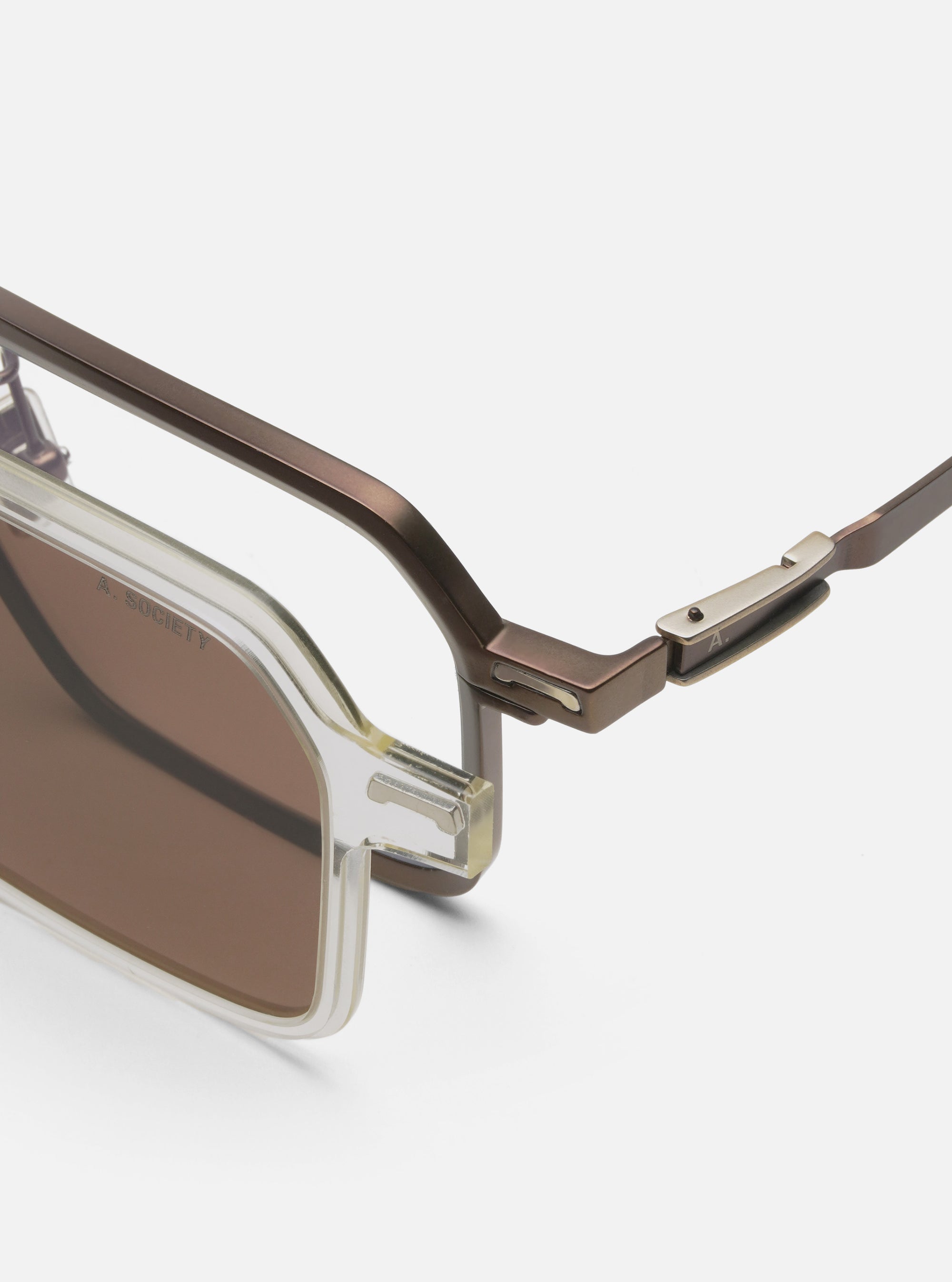 Close-up of A. SOCIETY x Universal Works Brown/Honey Kowloon Eyewear on a white surface. Features brown frames and honey-tinted lenses. Stylish and modern design.