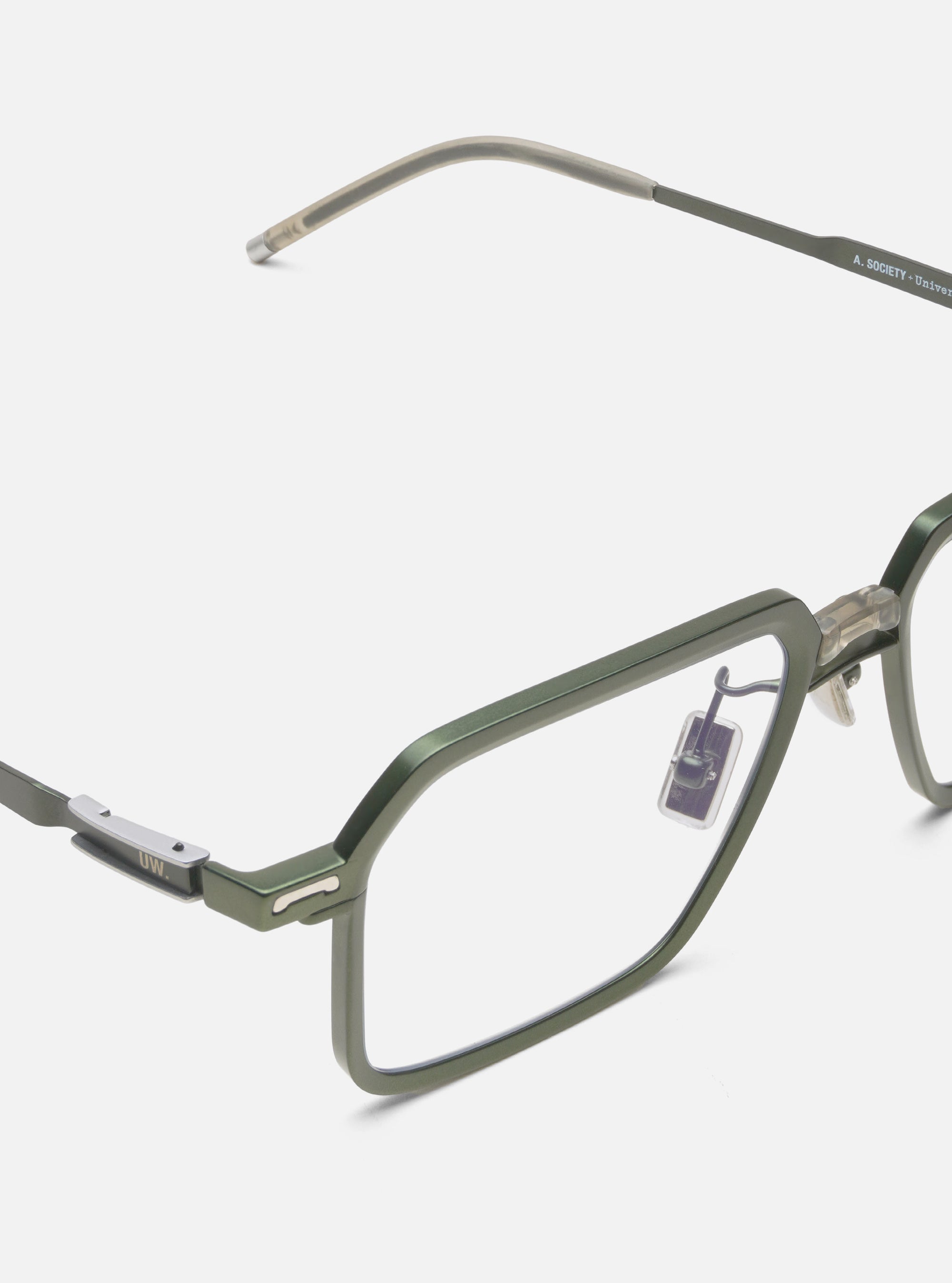 Close-up of A. SOCIETY x Universal Works Olive/Green Kowloon Eyewear on a white background. The glasses have a green metal frame and clear lenses.