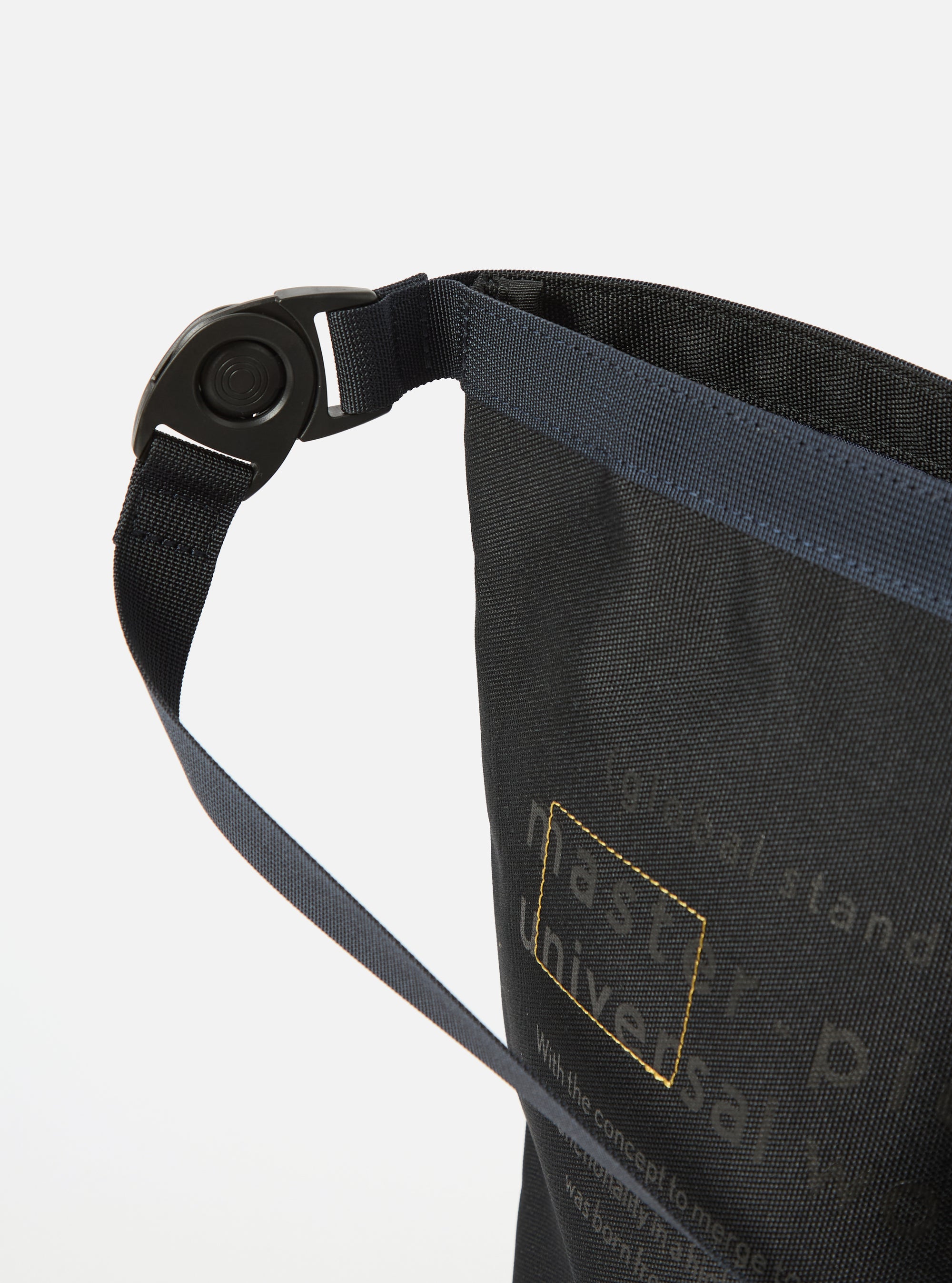 Close-up of the master-piece x Universal Works Black Recycled Tech Canvas Large Tote Bag. The black canvas material is visible with gold accents. Shot against a white background.