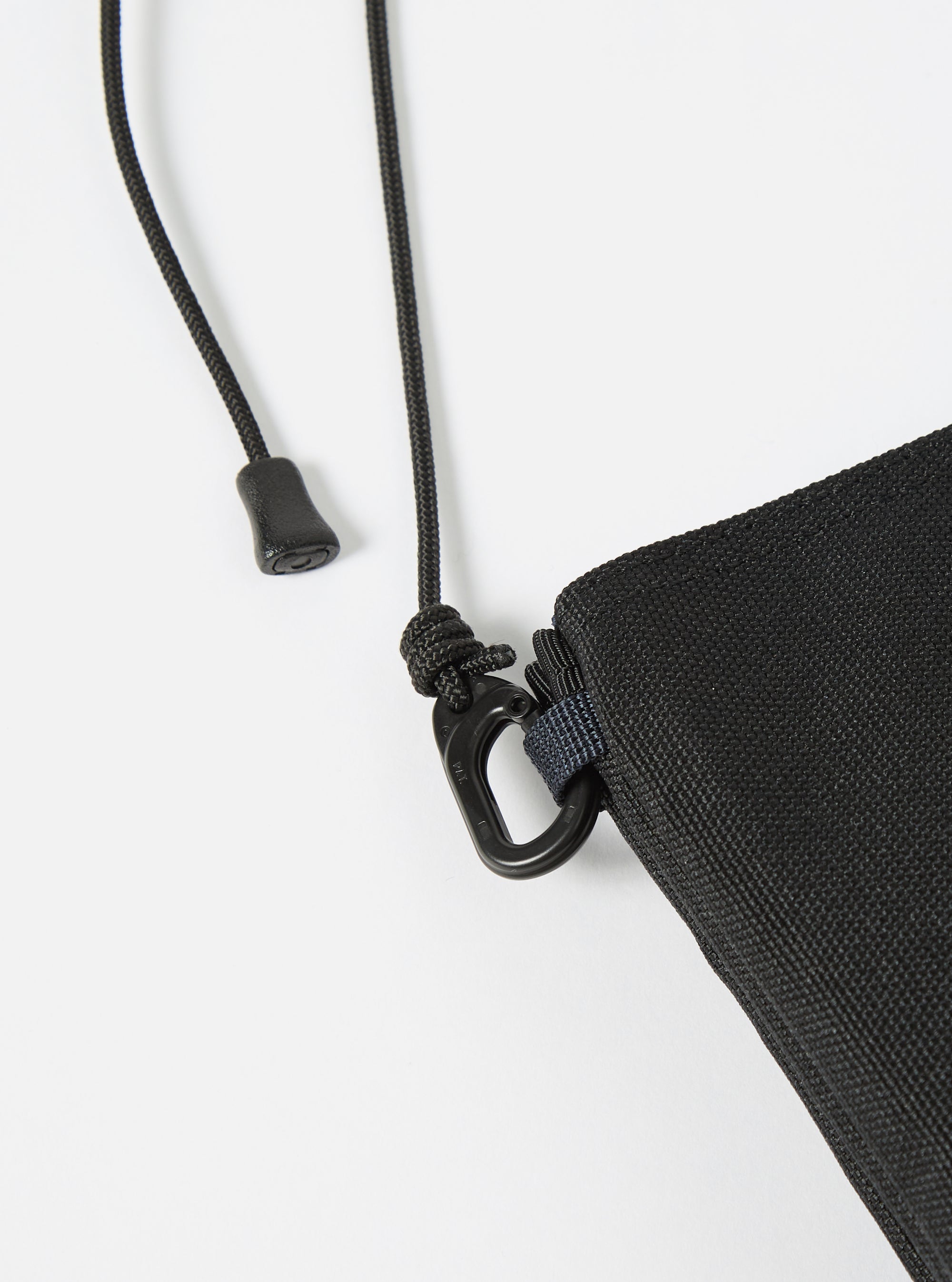 Close-up of the master-piece x Universal Works Black Recycled Tech Canvas Sacoche showing the black tech canvas material, black rope strap, and metal hardware on a white background.